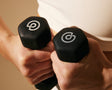 Trainer hands holding 2 lb. hand weights together showing logos