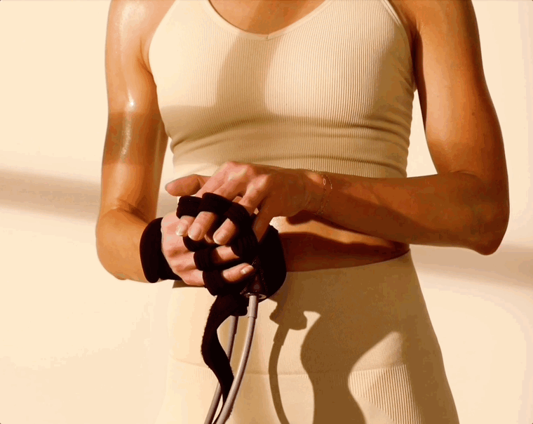 Person in beige workout attire adjusting fitness resistance bands.